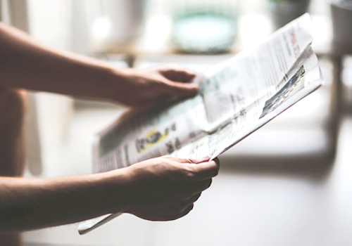 Eine Person hält eine Zeitung in der Hand